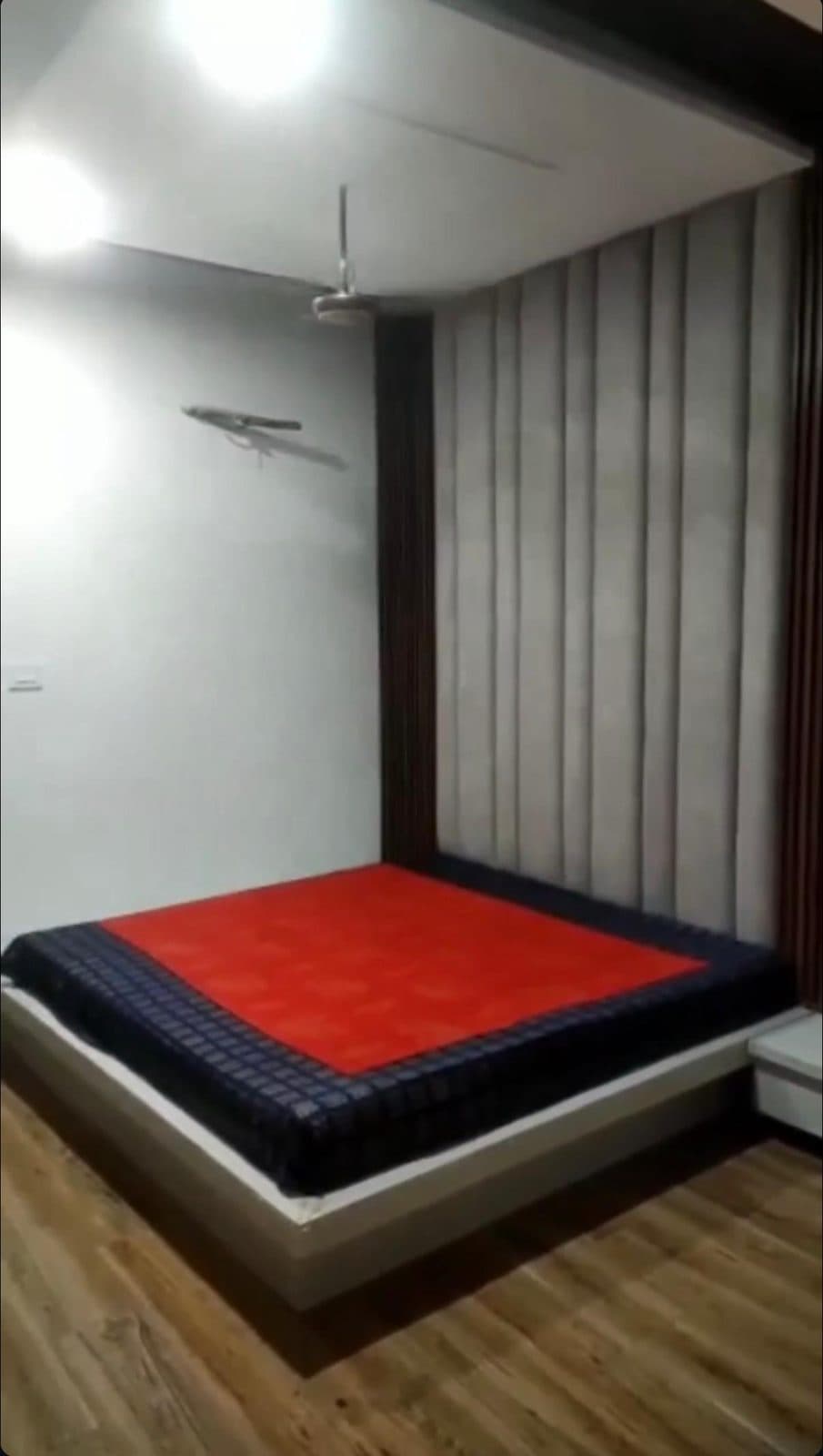 Master bedroom with a platform bed, grey upholstered headboard wall and wooden flooring